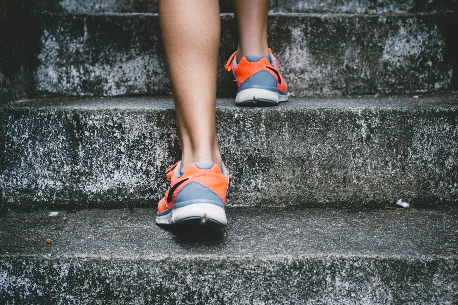 A person climbing outdoor stairs in running shoes